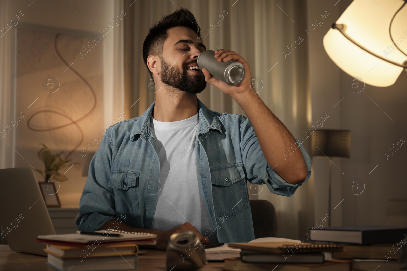 Photo of Young man with energy drink studying at home