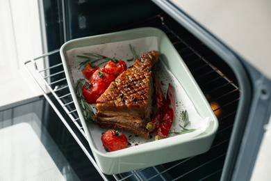 Photo of Delicious roasted ribs with tomatoes in oven