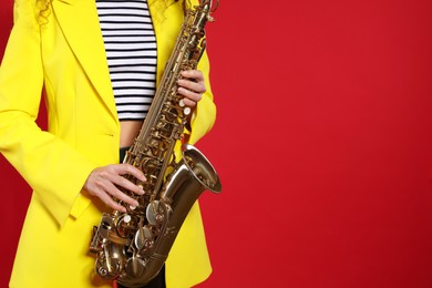 Woman with saxophone on red background, closeup. Space for text