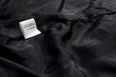 Clothing label on black garment, space for text