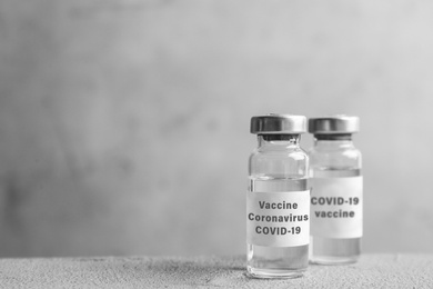 Coronavirus vaccine on grey table, space for text