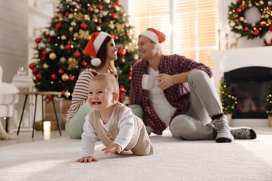 Photo of Happy family in room decorated for Christmas, focus on baby