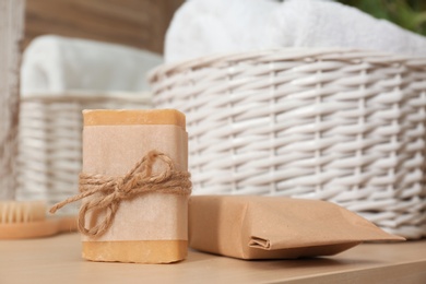 Photo of Soap bar near laundry basket on table. Space for text