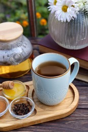 Tray with delicious tea and ingredients on wooden table