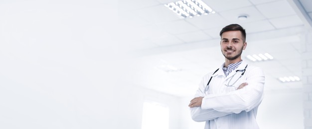 Young doctor in uniform at workplace, space for text. Banner design