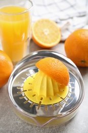 Photo of Fresh ripe oranges, juice and squeezer on grey table