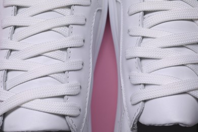 Photo of Pair of stylish white sneakers on pink background, closeup