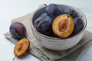 Tasty ripe plums on white table, closeup