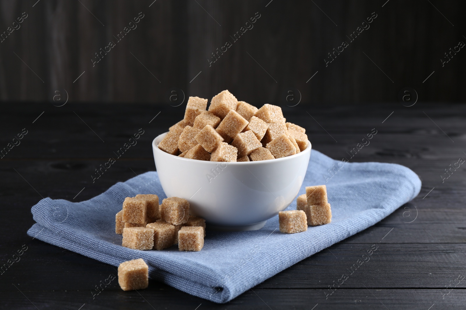 Photo of Brown sugar cubes on black wooden table