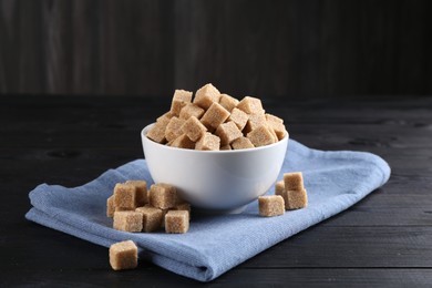 Photo of Brown sugar cubes on black wooden table