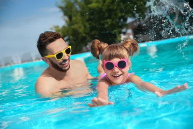 Photo of Father and daughter having fun in swimming pool. Family vacation