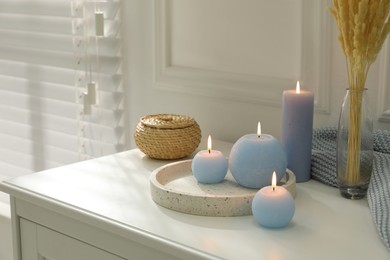 Photo of Burning candles on white countertop in room