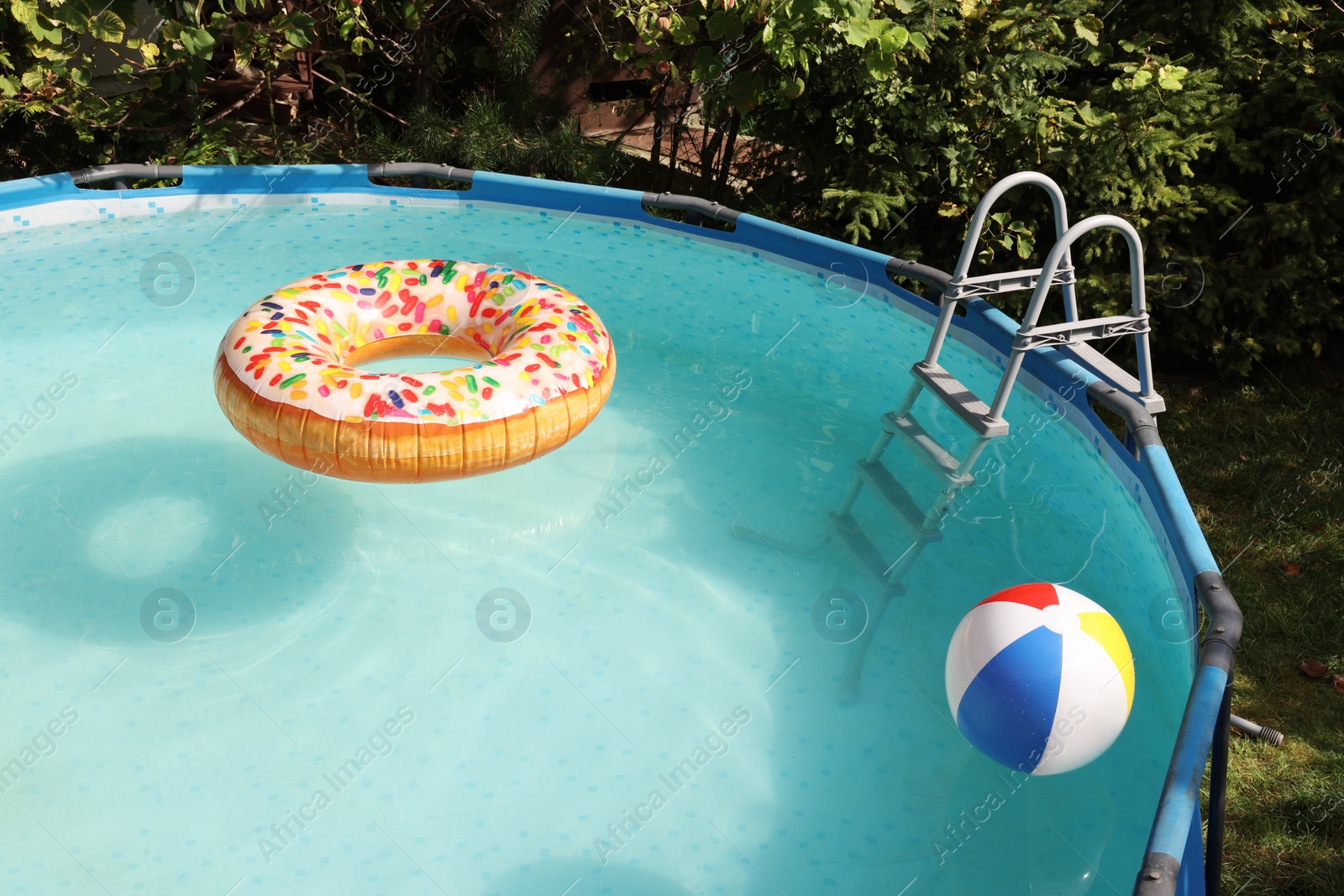 Photo of Inflatable ring and ball floating on water in above ground swimming pool outdoors