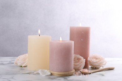 Spa composition with burning candles, flowers and sea salt on white marble table