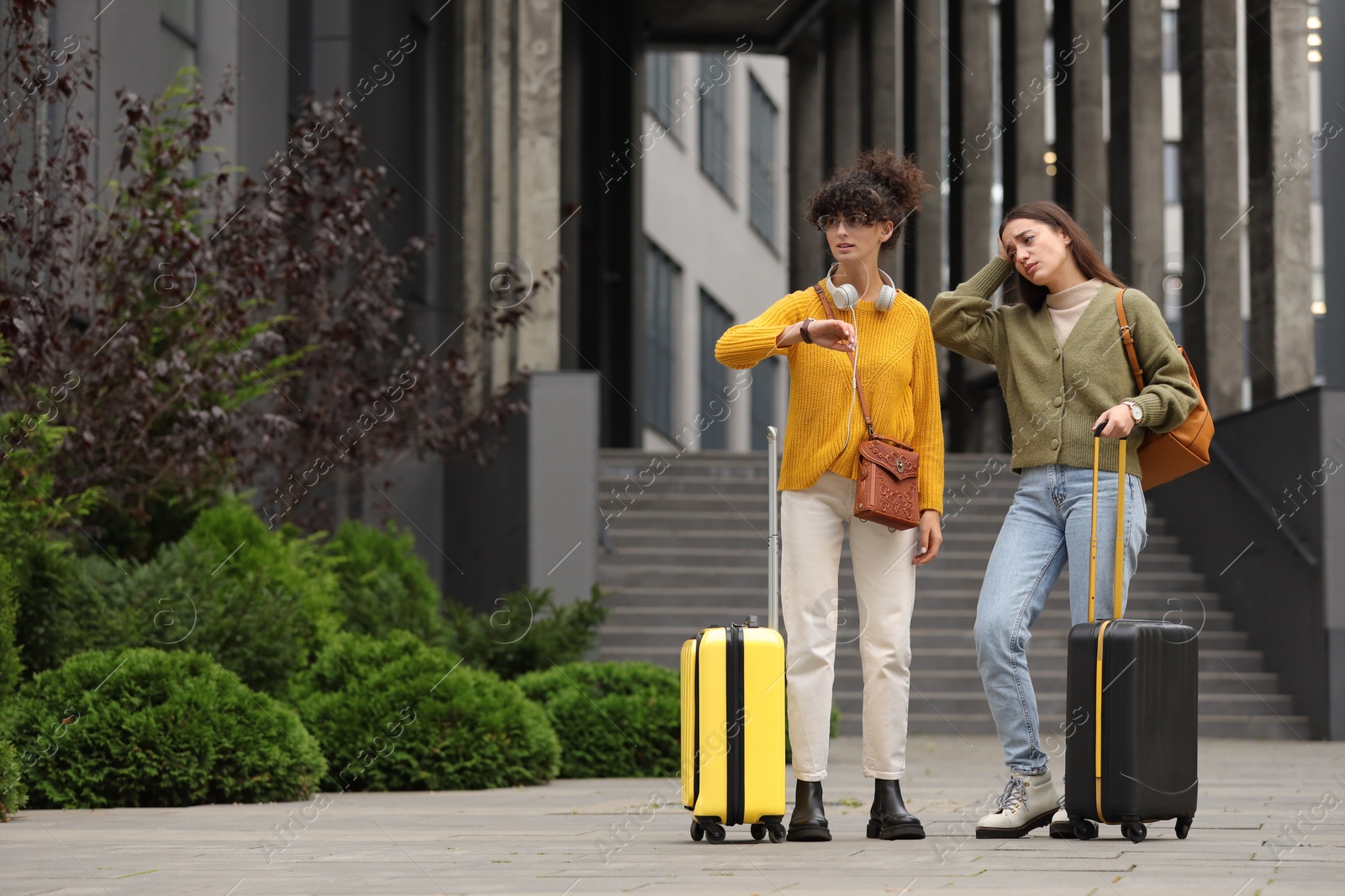 Photo of Being late. Worried women with suitcases near building outdoors, space for text