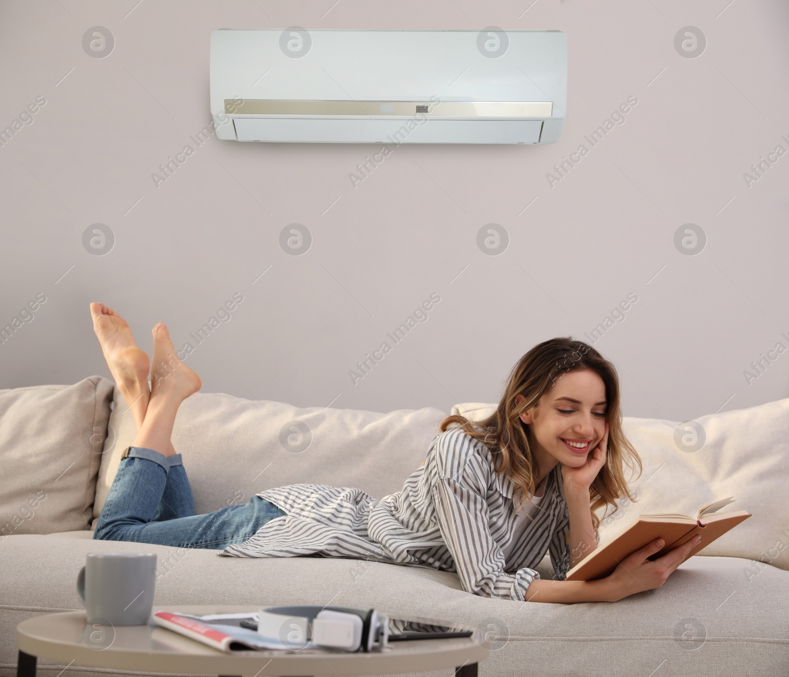 Image of Young woman resting under air conditioner on white wall at home