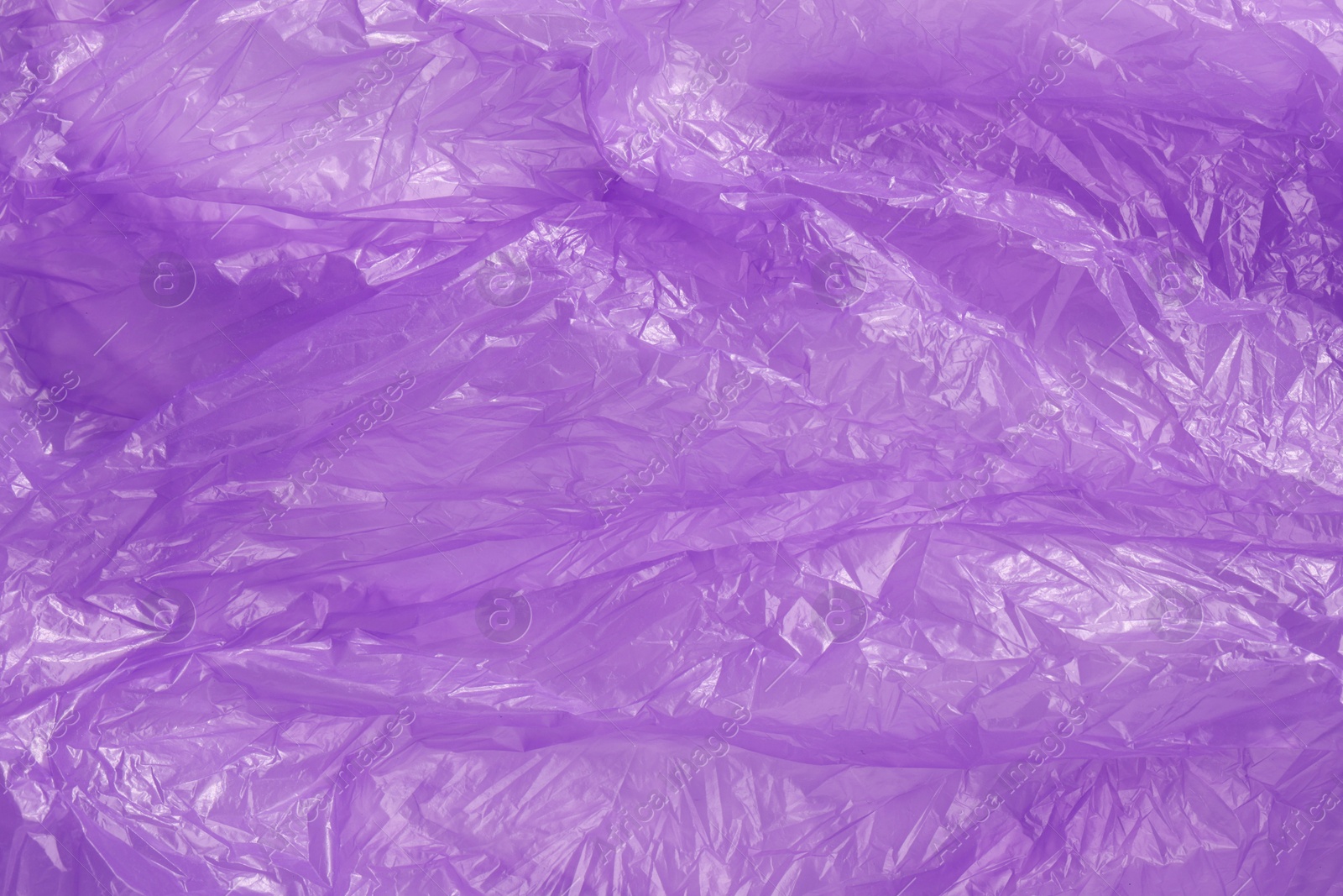 Photo of Crumpled purple plastic bag as background, top view