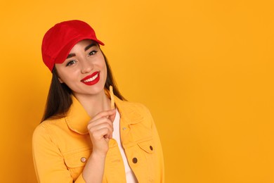 Beautiful young woman eating French fries on yellow background. Space for text