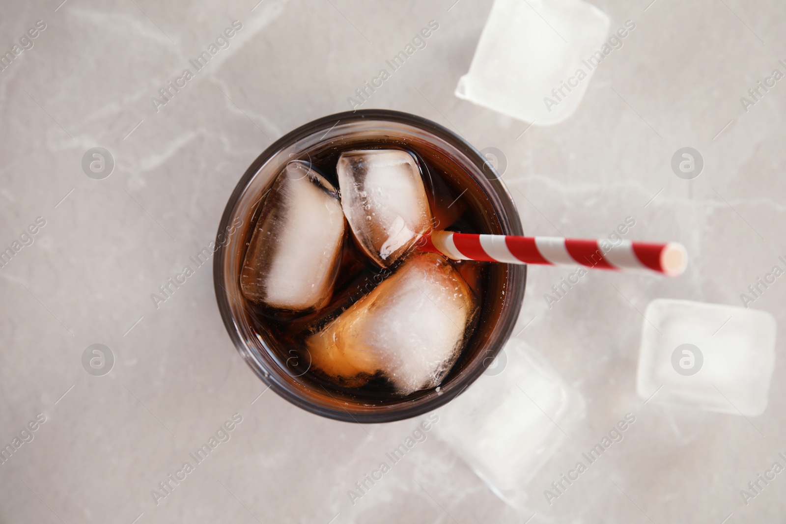 Photo of Glass of cola with ice on grey background, top view