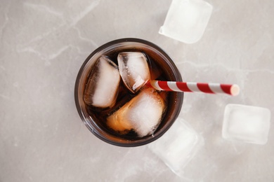 Photo of Glass of cola with ice on grey background, top view