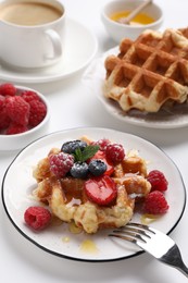 Photo of Delicious Belgian waffle with fresh berries and honey served on white table