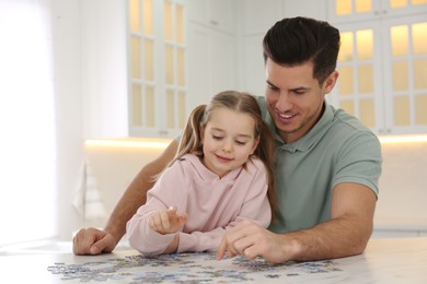 Photo of Man and his little daughter playing with puzzles at home