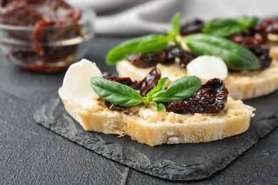 Slate plate of delicious tomato bruschettas on black table, closeup