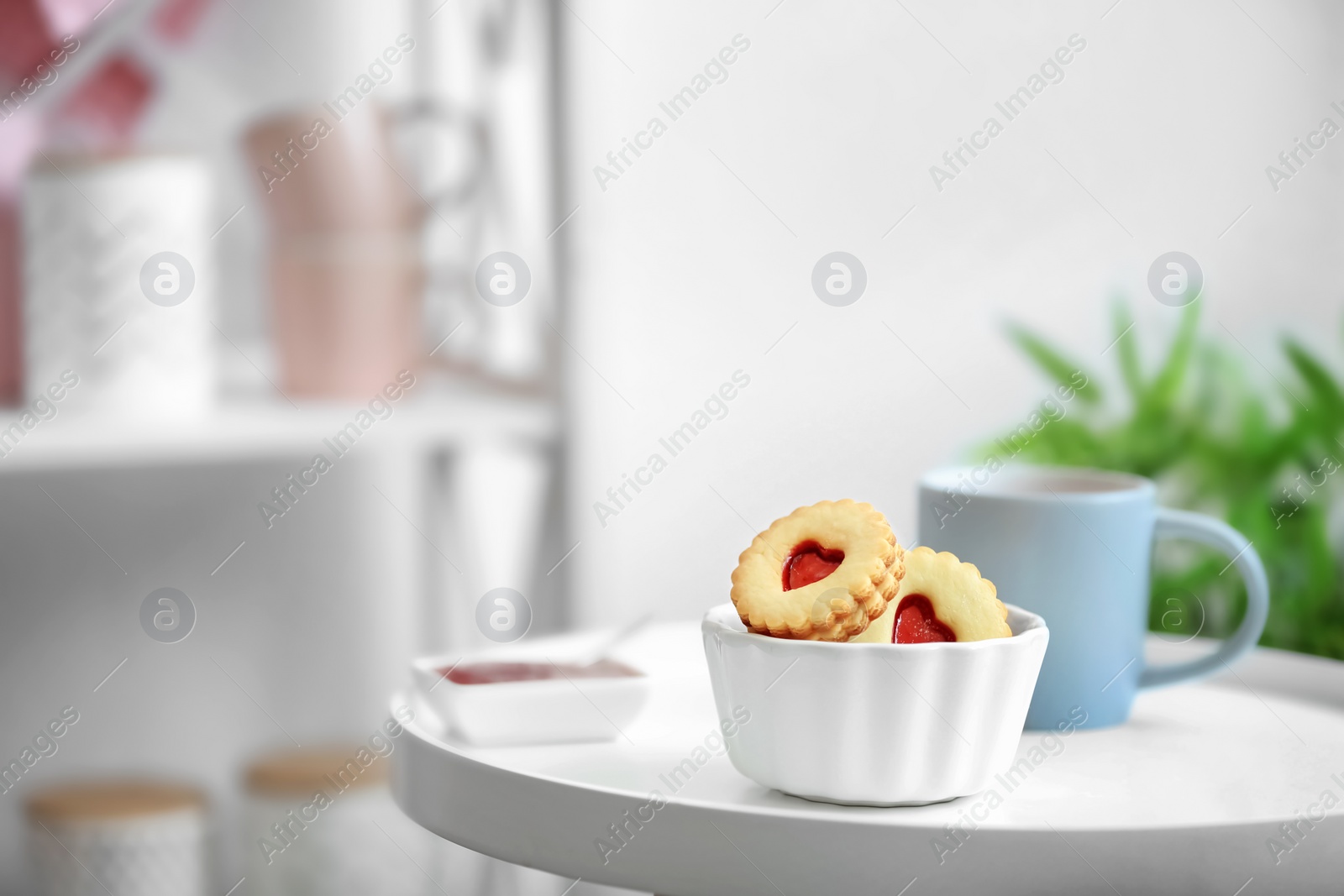 Photo of Traditional Christmas Linzer cookies with sweet jam and cup of tea on table