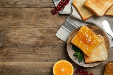 Photo of Delicious toasts served with jam, orange and berries on wooden table, flat lay. Space for text