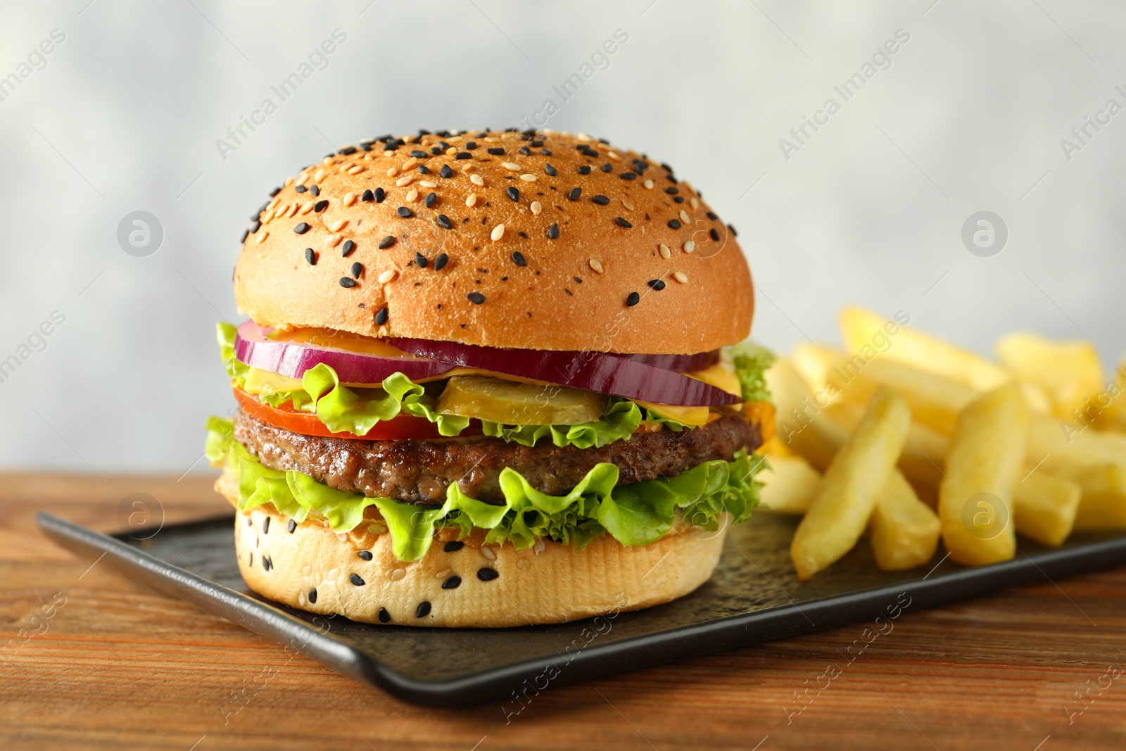 Burger with delicious patty and french fries on wooden table, closeup Photo of Burger with delicious patty and french fries on wooden table, closeup