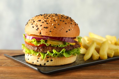 Photo of Burger with delicious patty and french fries on wooden table, closeup
