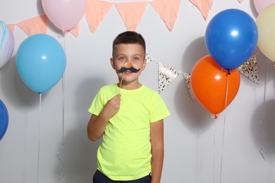 Happy boy near bright balloons at birthday party indoors