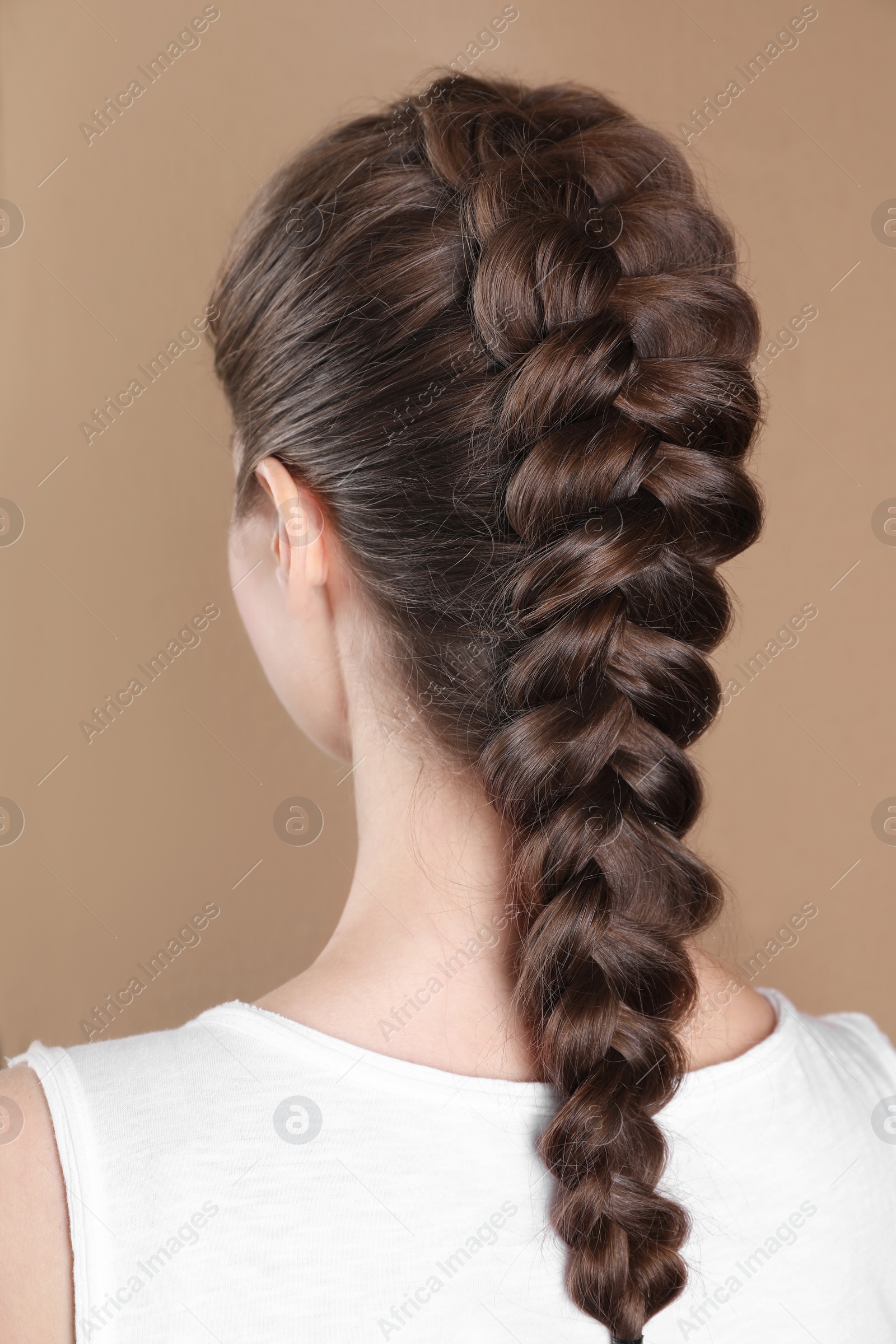 Photo of Woman with braided hair on light brown background, back view