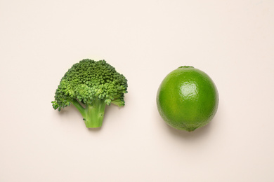 Photo of Fresh tasty broccoli and lime on light beige background, flat lay