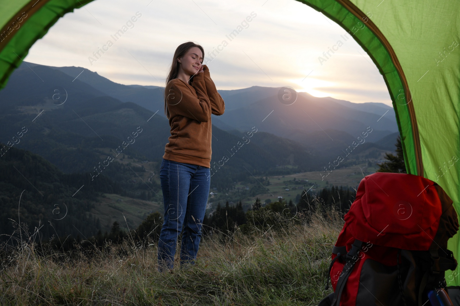 Photo of Young woman in mountains, view from camping tent