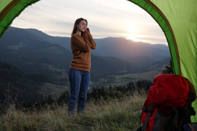 Young woman in mountains, view from camping tent