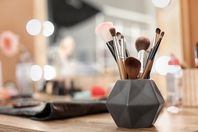 Holder with makeup brushes on table