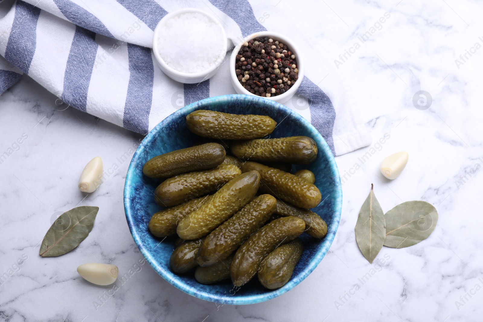 Photo of Bowl of pickled cucumbers and ingredients on white marble table, flat lay