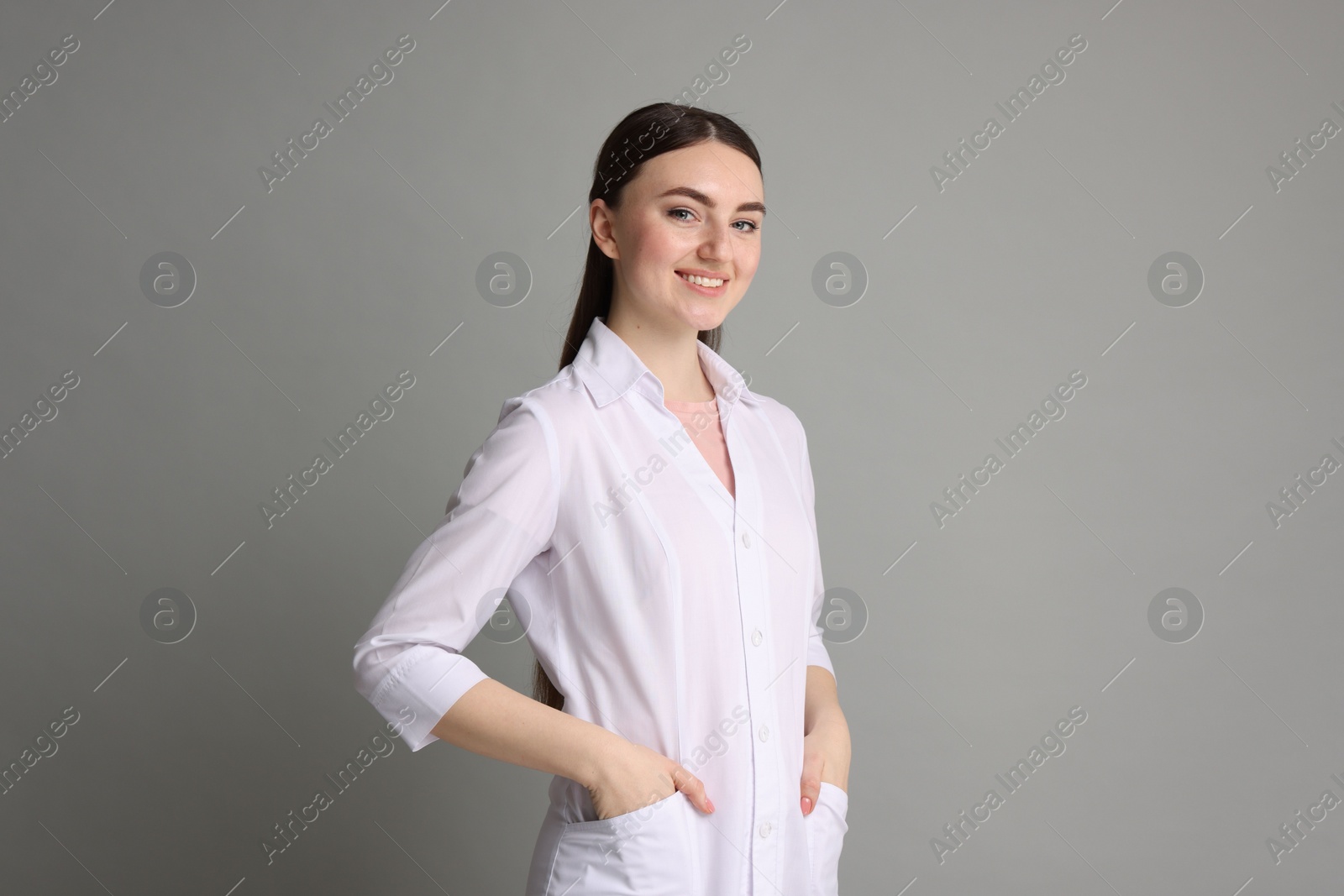 Photo of Cosmetologist in medical uniform on grey background