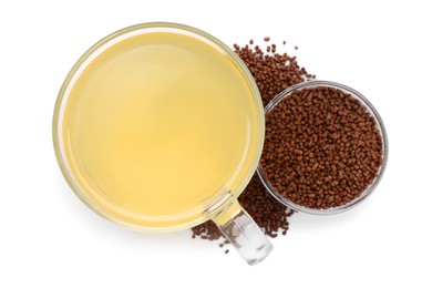 Cup of aromatic buckwheat tea and granules on white background, top view