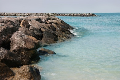 Photo of Picturesque view of beautiful rocky beach with breakwater on sunny day