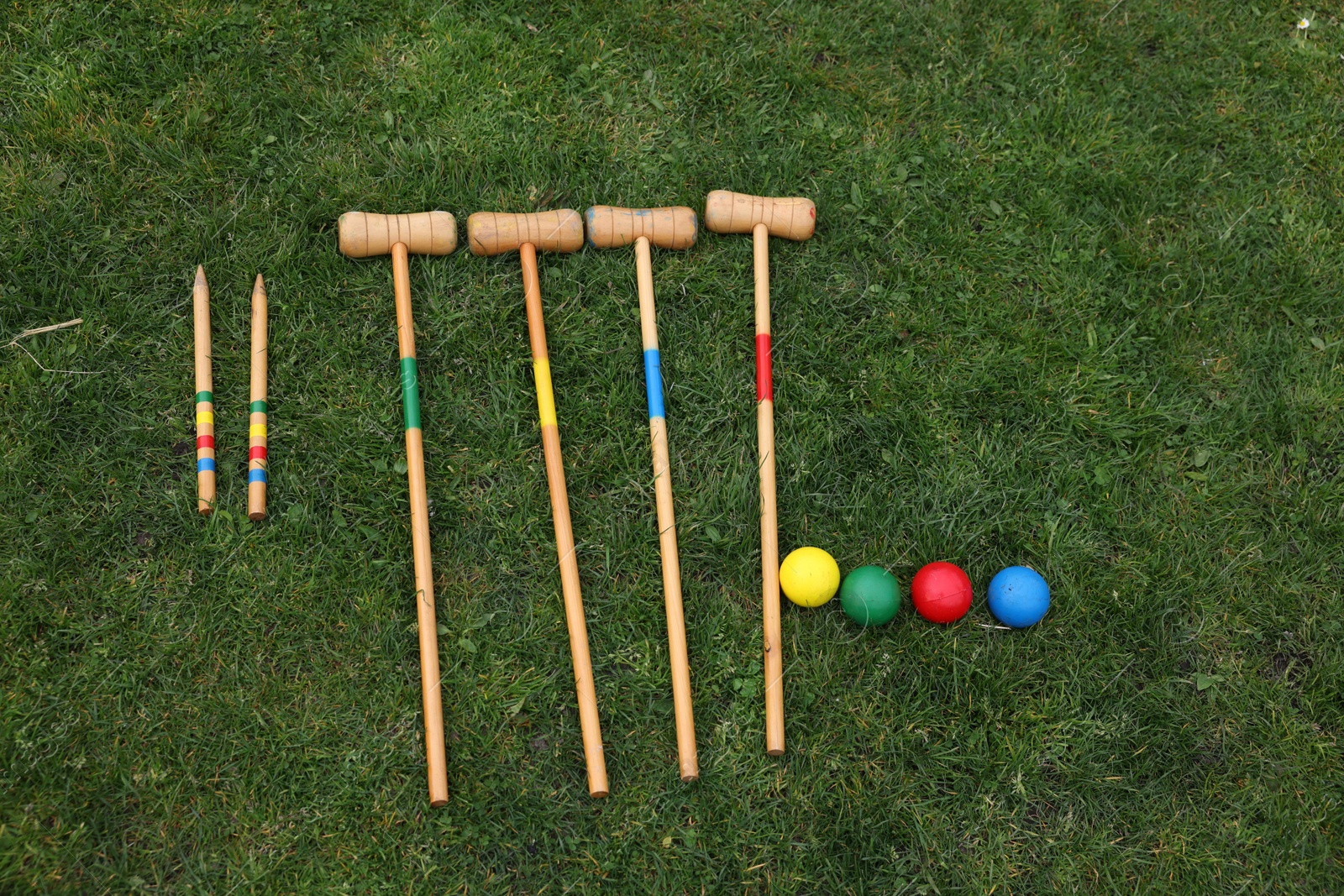 Photo of Set of croquet equipment on green grass, flat lay