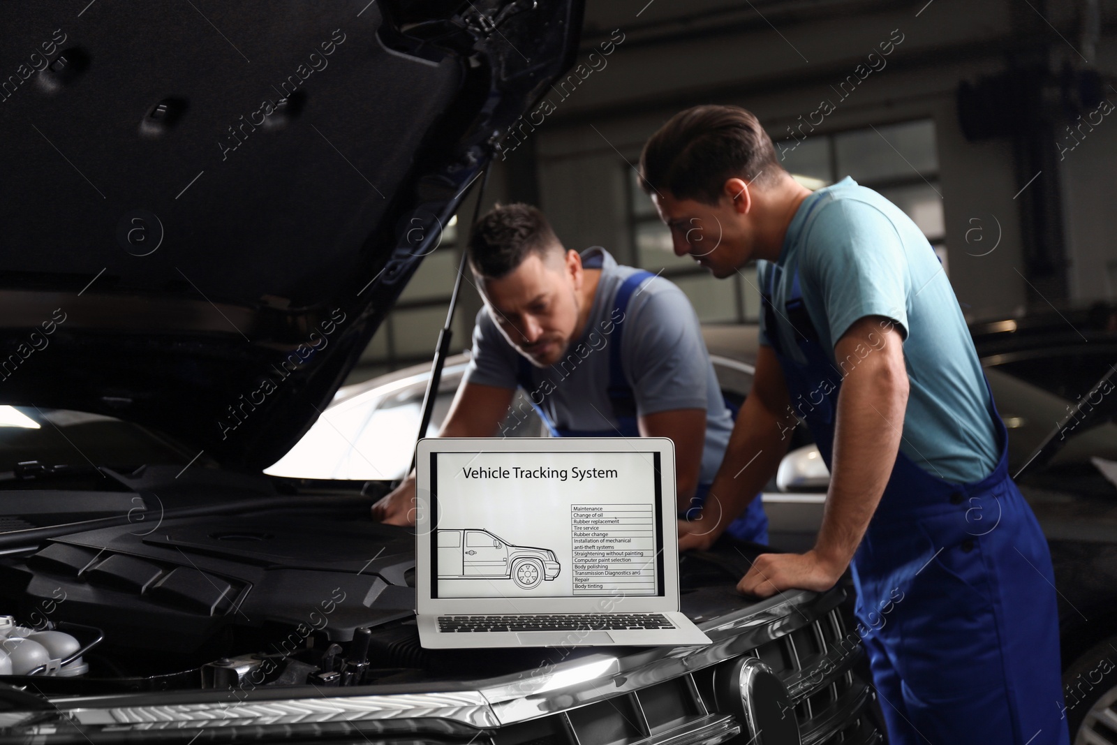 Photo of Laptop with vehicle tracking system and blurred mechanics on background. Auto diagnostic