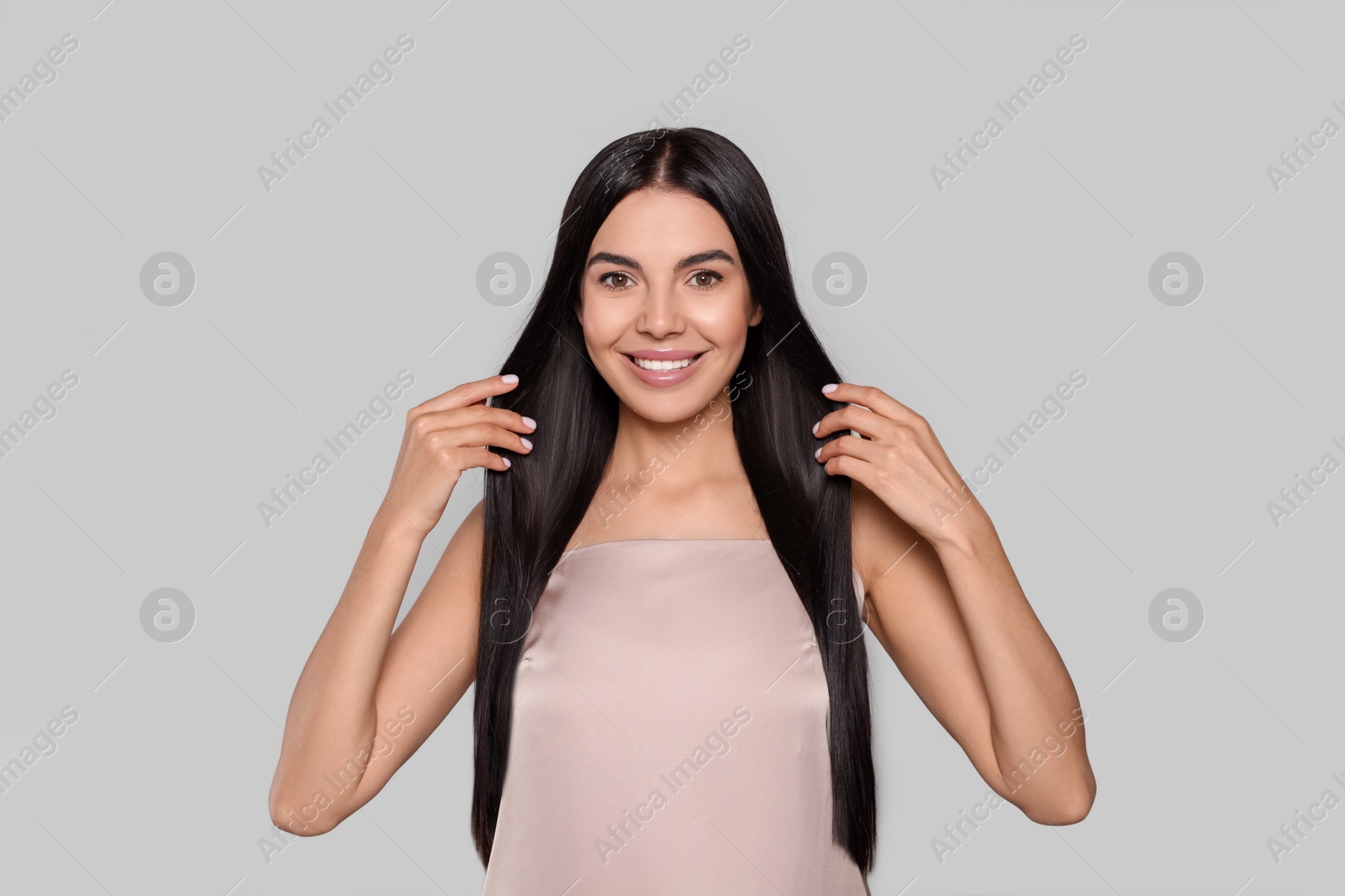 Photo of Portrait of beautiful young woman with healthy strong hair on light grey background