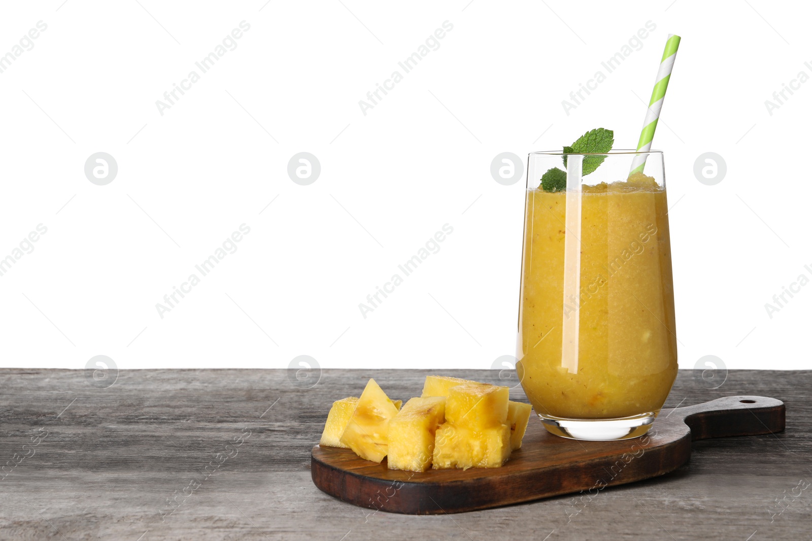 Photo of Glass of tasty pineapple smoothie and cut fruit on wooden table against white background, space for text