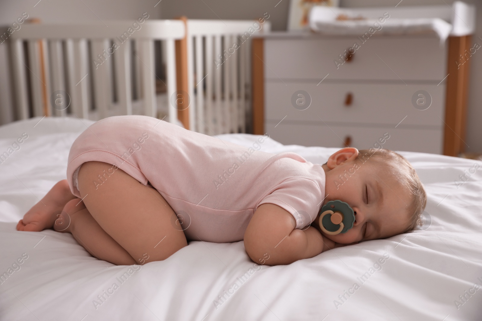 Photo of Adorable little baby with pacifier sleeping on bed at home