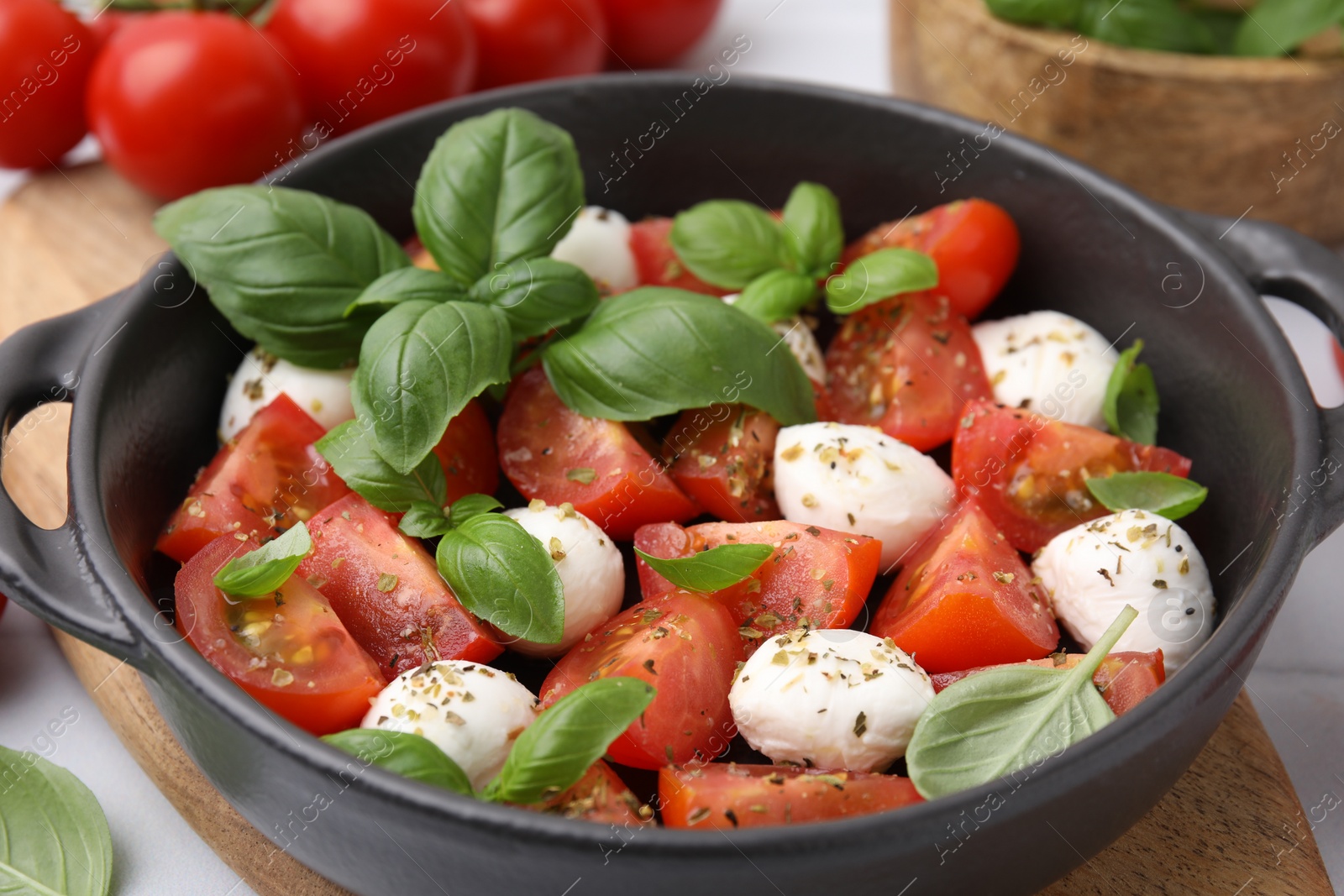 Photo of Tasty salad Caprese with mozarella balls, tomatoes and basil on table, closeup