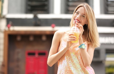 Photo of Young woman with cup of tasty lemonade outdoors