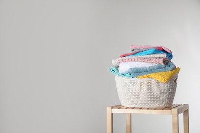 Photo of Laundry basket with clean towels on table against light background. Space for text