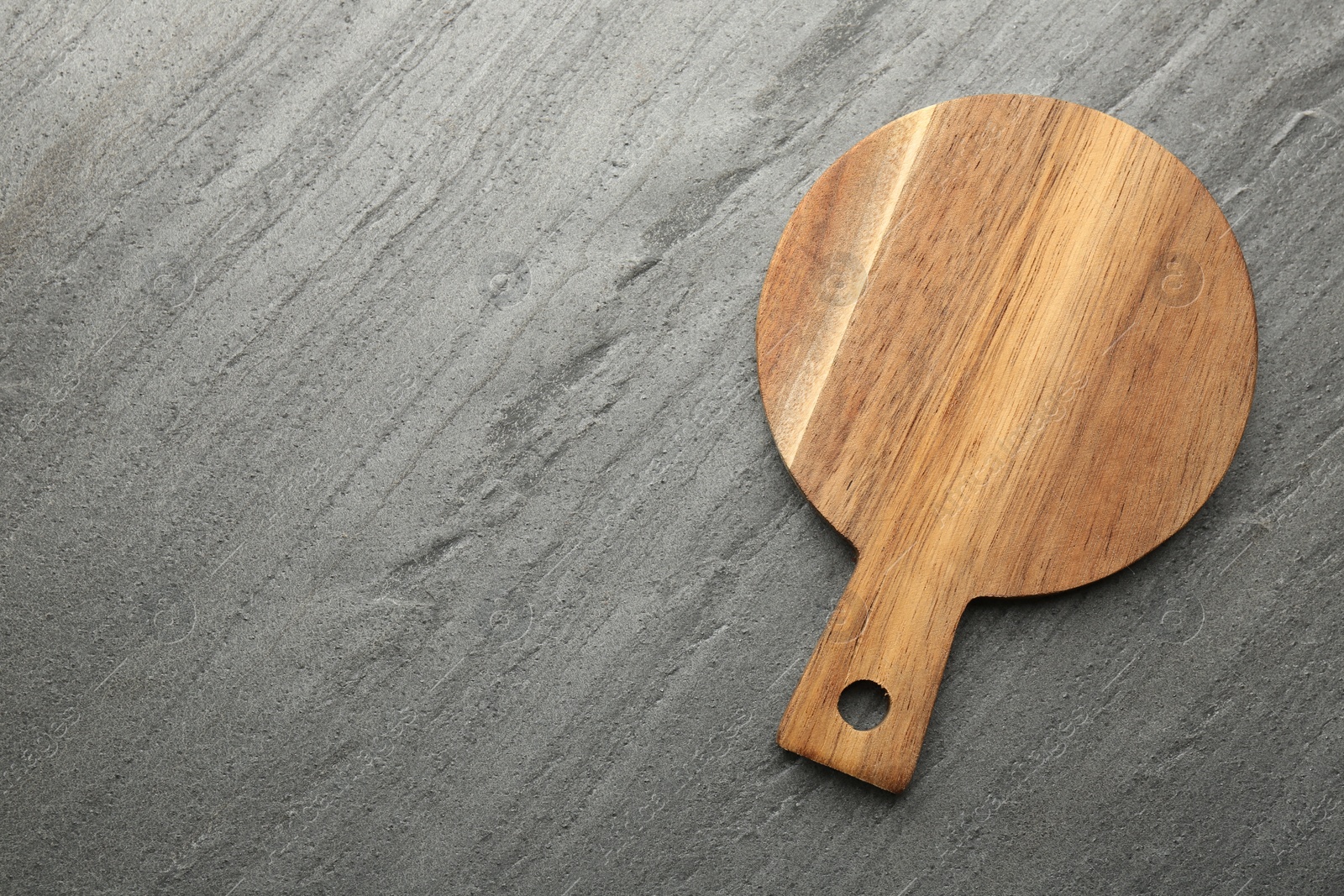 Photo of One wooden cutting board on dark grey table, top view. Space for text